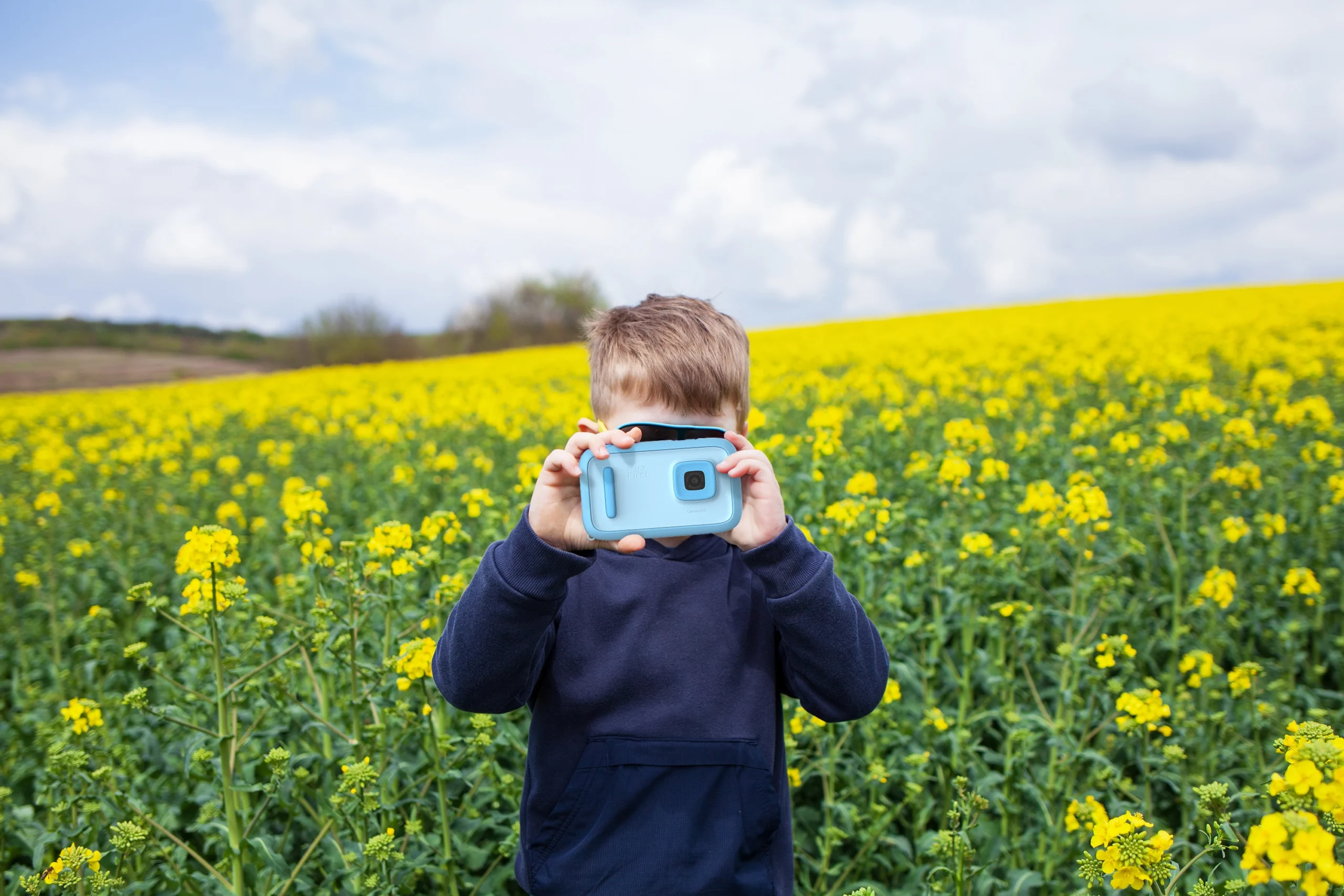 Niño en un campo de flores disfrutando con la myfirst camera 50
